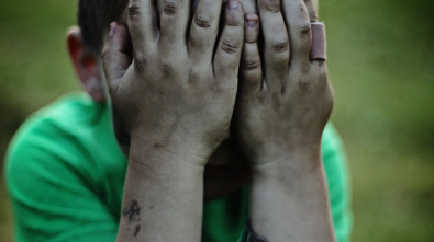 boy sitting while covering his face