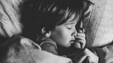 grayscale photo of girl sleeping on white pillow